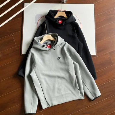 Grey half-zip sweatshirt laid flat on a wooden floor beside a dark jacket