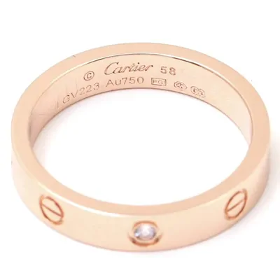 Close-up of a rose gold band ring with screw motifs around it