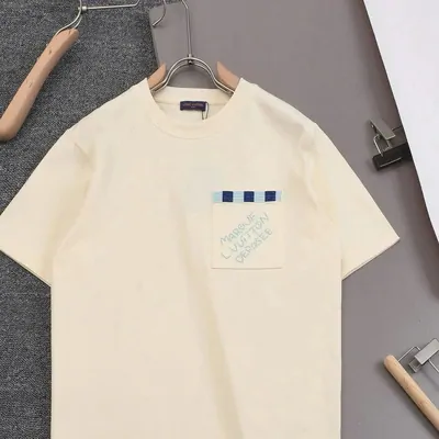 Cream short-sleeve tee on a wooden hanger against a grey wall