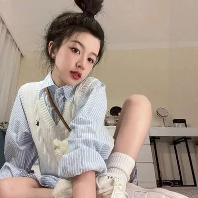 Seated model in an oversized white shirt with a small shoulder bag